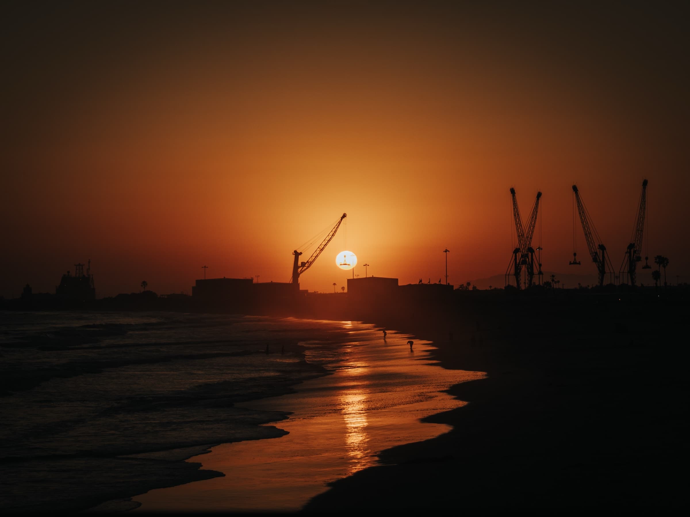 Harbor cranes against the setting sun