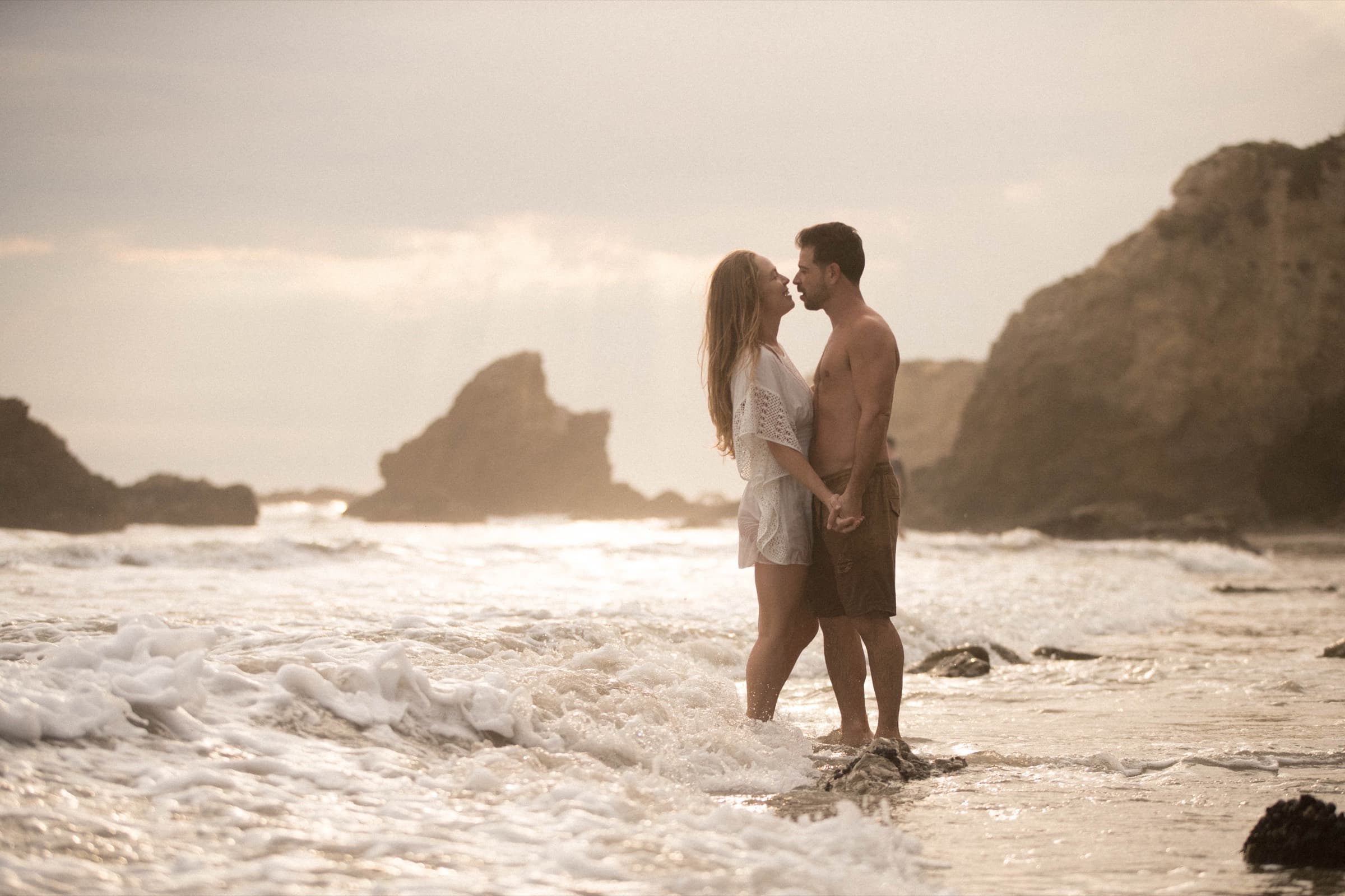 A couple standing together in the surf at golden hour