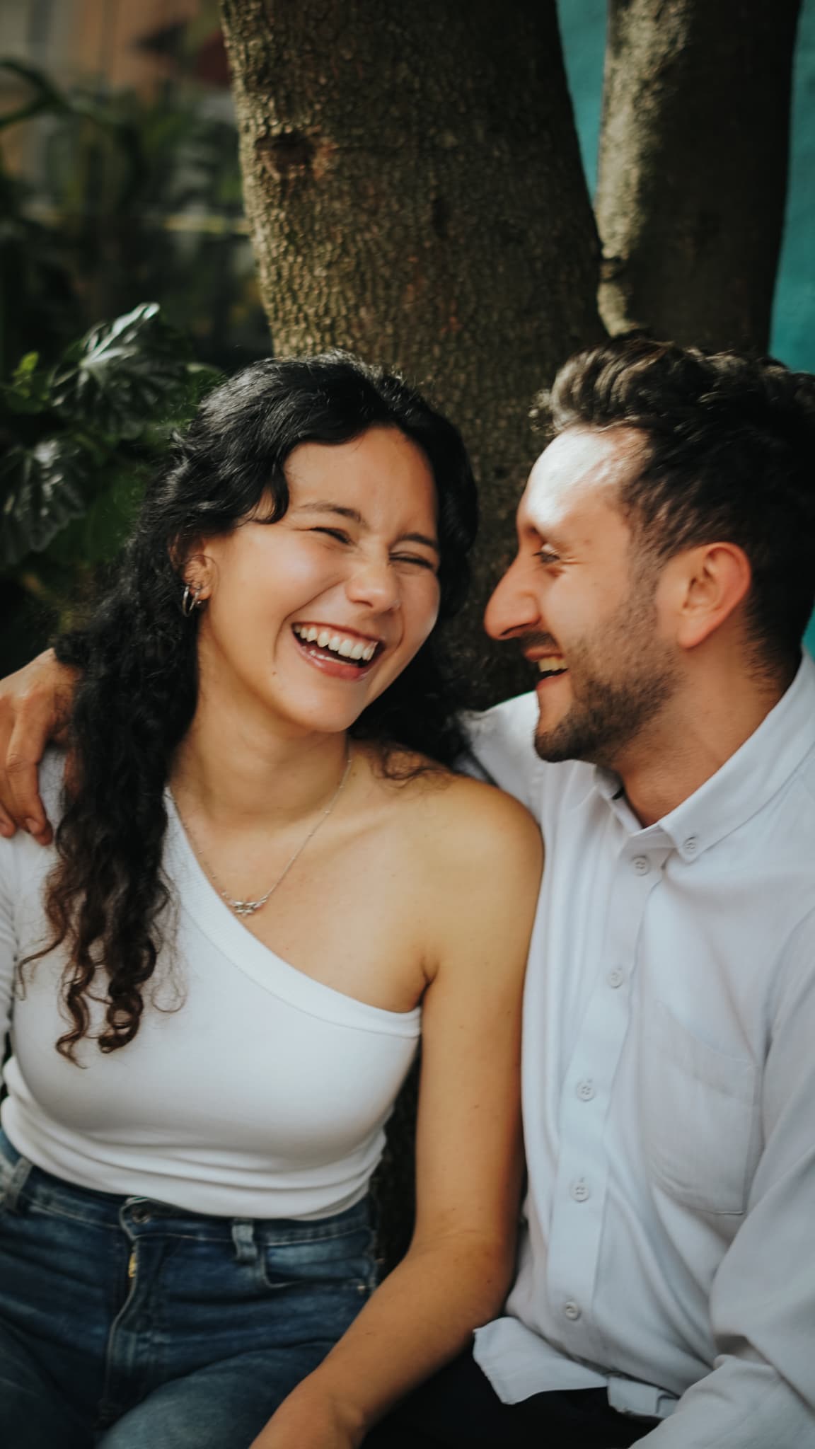 A couple laughing together beneath a tree
