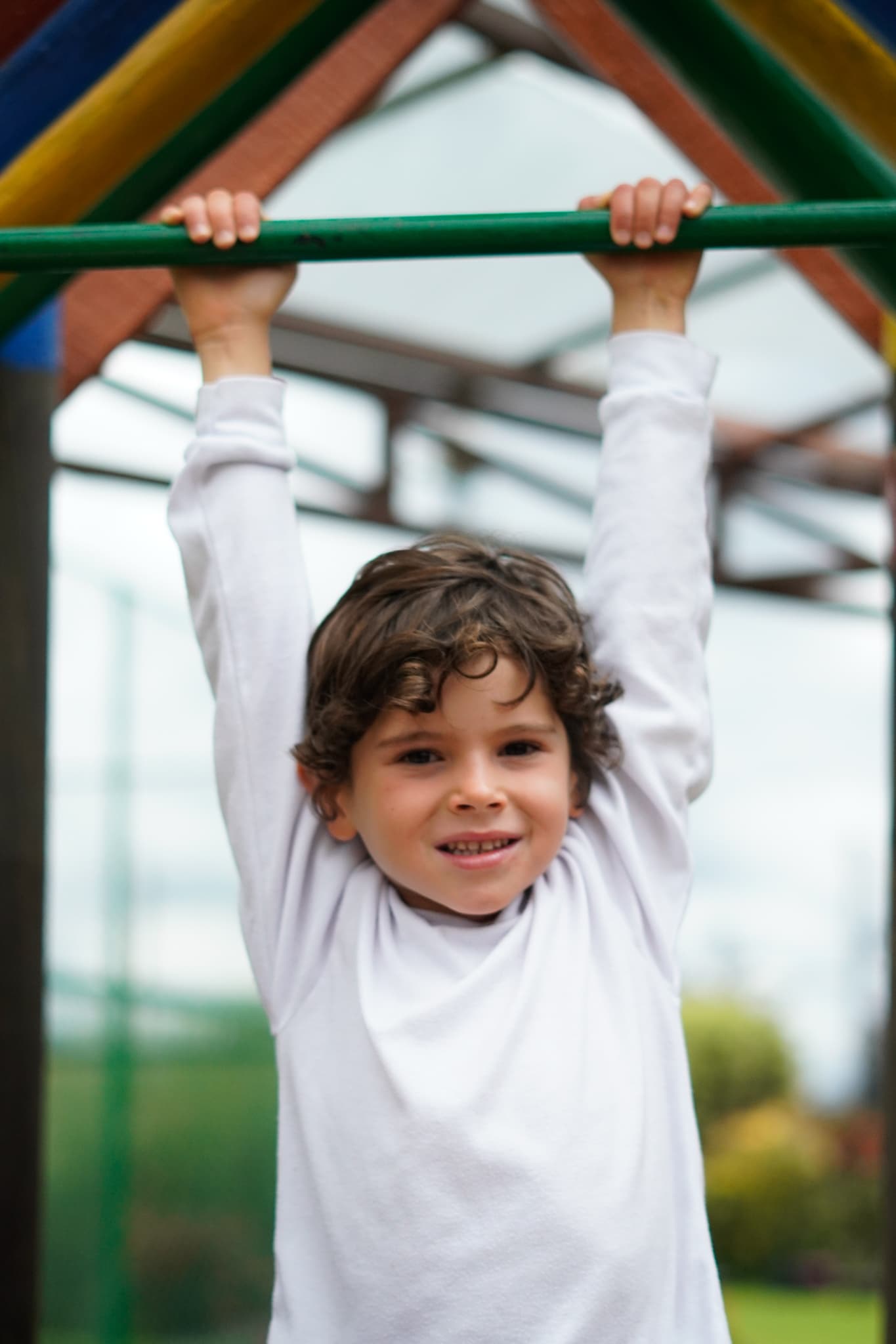 A boy swinging from the playground bars