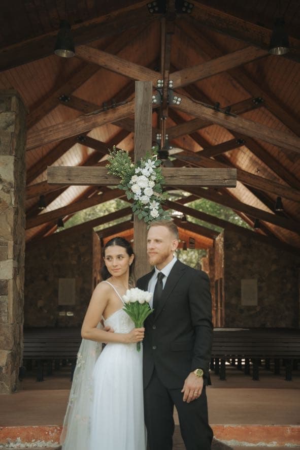 Bride and groom before the floral cross in the open-air chapel