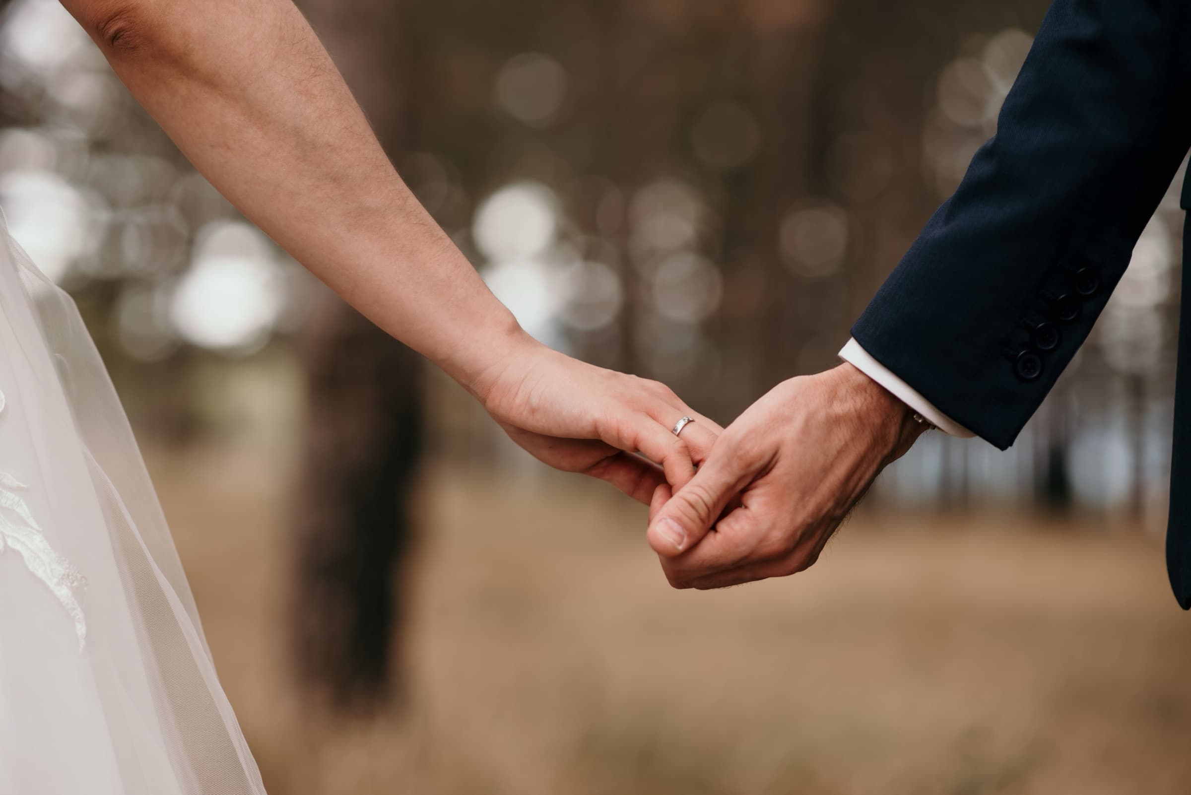 Couple holding hands during the ceremony in a natural setting