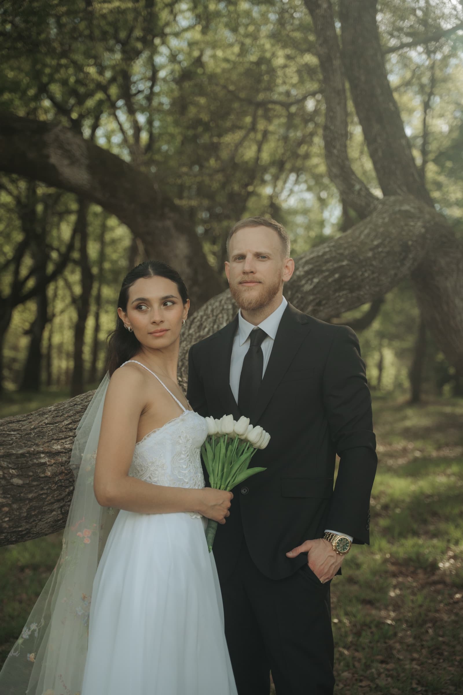 Bride and groom in the woods, white tulips in hand