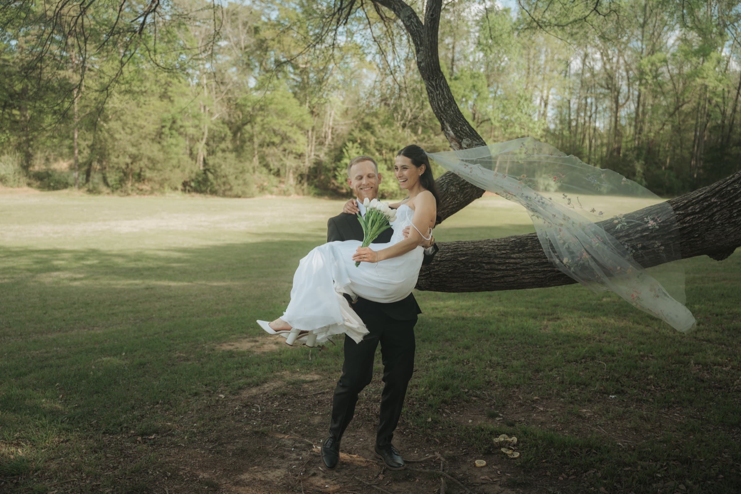 Groom carrying the bride beneath the oaks