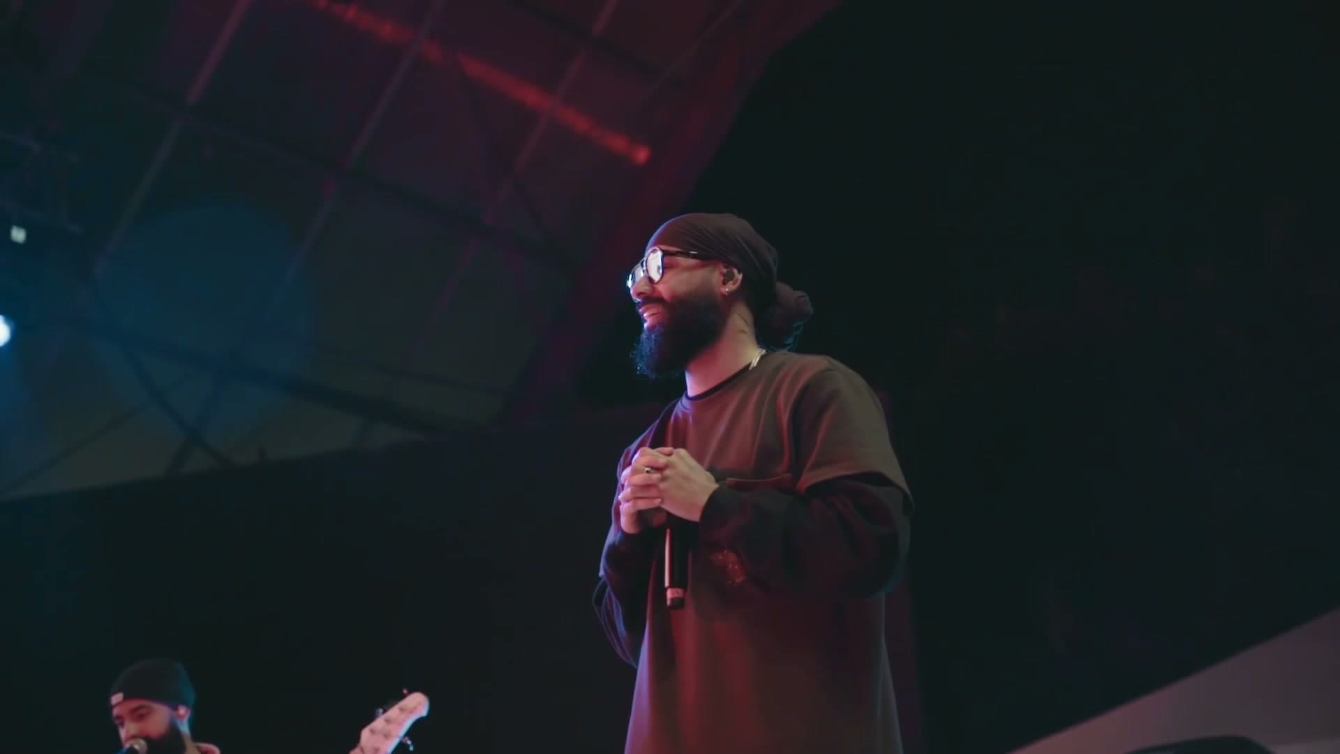 A performer on stage under red and teal lighting